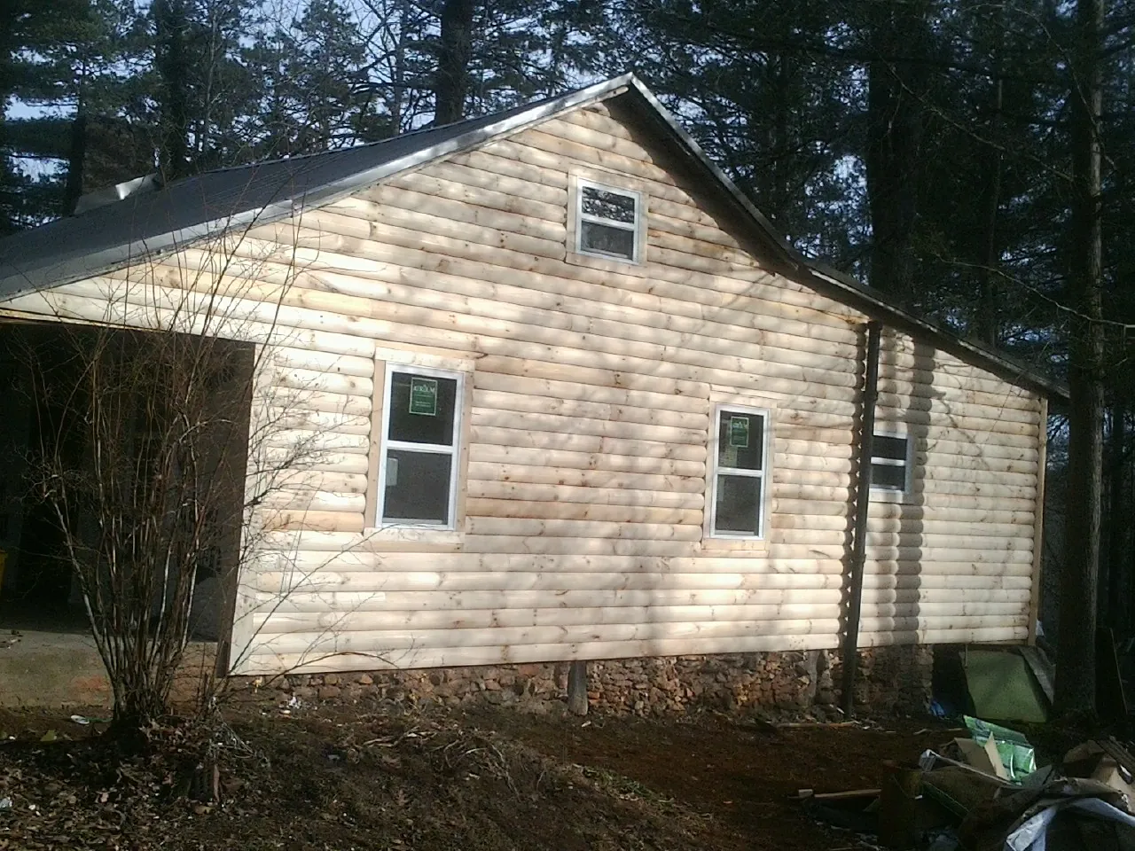 New log siding and dark metal roofing on a gable end in Versailles