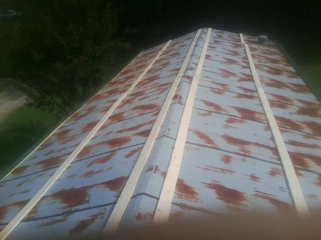 Rusted metal roof panels with new wood purlins before replacement — Storm Damage Roof Repair in Versailles by Roofing Brothers
