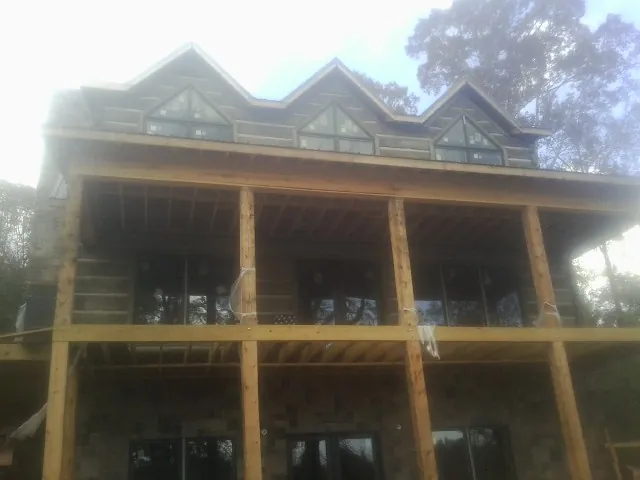 Dormers and porch framing on a large log home under construction — Roof Coating work by our crew in Versailles